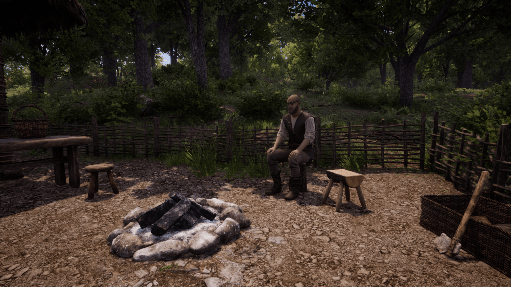Sambor sitting on a stump by his fire at his house.